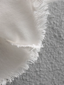Dettaglio macro del tessuto bianco con bordi sfilacciati alla moda e trama in misto cotone