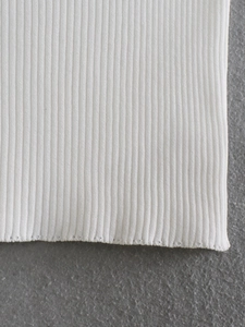 Macro shot of white ribbed knit fabric showing fine texture and hemline craftsmanship
