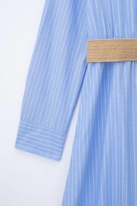 Détail d'une robe chemise à rayures bleu clair avec une ceinture tressée style paille