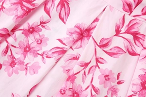 Makroaufnahme von rosa Blumenmuster-Stoff mit Faltenstruktur und feinen Nahtdetails