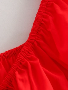 Detail view of red smocked elastic fabric and neat stitching on a summer off-shoulder top