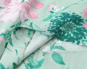 Close-up of floral print linen blend fabric showing detailed hem stitching and pink flowers