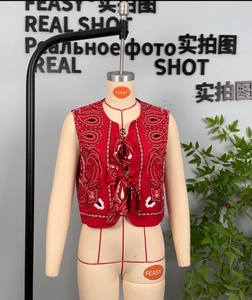Detail of red paisley print vest with front tie closure on a mannequin display