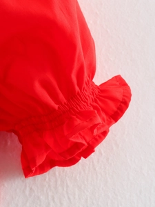 Detailed macro shot of the red ruffled elastic cuffs with shirring design on the sleeve