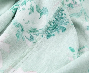 Detail of light green floral linen blend fabric with refined stitching and floral pattern