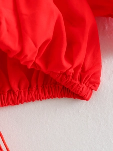 Detailed view of red top with elastic cuff and matching drawstring closure detail