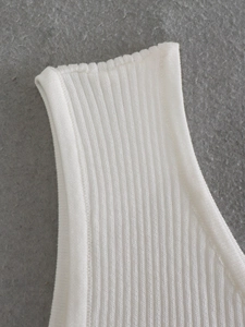 Detailed close-up of white ribbed knit fabric texture on a modern women's shoulder top