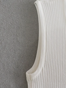 Detailed close-up of white ribbed knit fabric texture and high-quality edge stitching