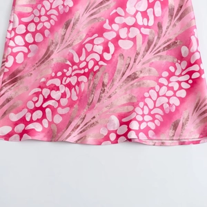 Detail of pink satin skirt showing abstract leaf print and smooth fabric texture