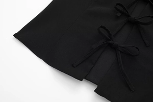 Détail du haut élastique noir avec nœuds décoratifs et texture de tissu tissé
