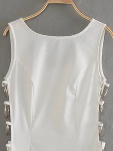 Detail of white sleeveless dress with side cut-outs and metallic silver ring decorations