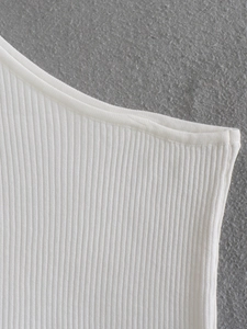 Close-up of white ribbed knit fabric showing vertical texture and neat stitching on shoulder