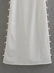 Detailed view of white dress side seam featuring decorative metal ring cut-out design