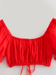 Detail view of red off-shoulder crop top with ruffles and adjustable drawstring ties