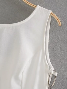 Detail of white sleeveless dress showing metal ring accent and plain weave fabric texture