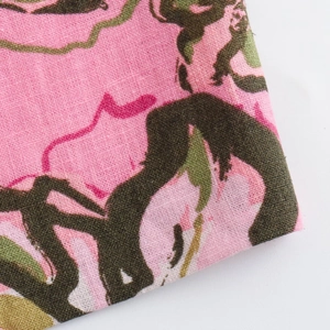 Dettaglio di tessuto misto lino rosa con stampa floreale verde e trama intrecciata