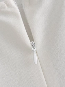 Close-up of a white invisible zipper detail on a slim fit dress with textured fabric