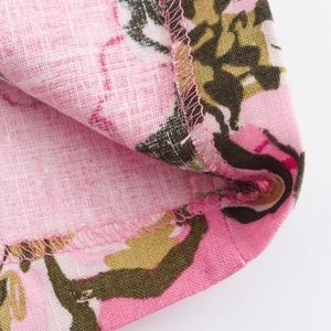 Vista macro del tessuto misto lino con stampa leopardata rosa e cuciture su un abito estivo