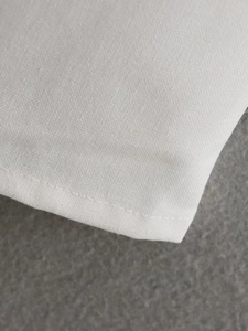 Detailed close-up of white fabric texture and neat stitching on a slim dress edge