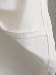 Macro shot of the neat stitching and woven texture on a white summer dress fabric