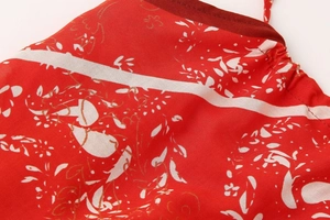 Détail macro du tissu à imprimé floral rouge avec texture satinée et liseré