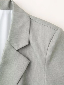 Close-up of peaked lapels and shoulder seams on a grey woven women's suit jacket