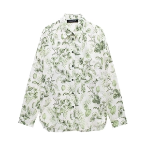 Détail d'une chemise fleurie à boutons avec base blanche, feuilles vertes et étiquette marque