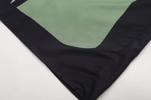 Close-up of olive green and black patchwork fabric with single needle stitching detail