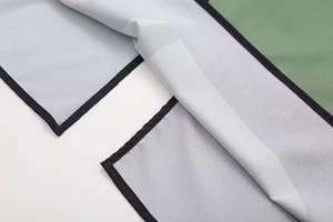 Macro shot of green and white color-block fabric with precise black piping details