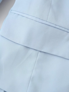 Détail de la robe plissée bleu clair montrant la texture du tissu et la poche cousue