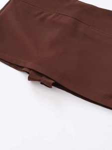 Detail of high-waist brown skirt featuring belt loops and precise stitching on fabric