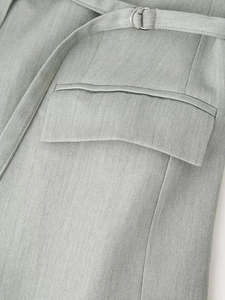 Detail of sage green woven fabric texture with silver D-ring belt buckle and pocket flap