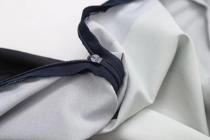 Close-up of high-quality smooth zipper on light gray fabric with navy blue tape