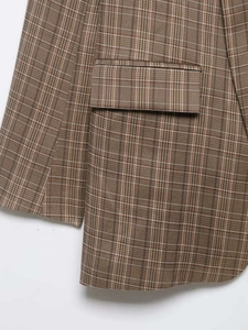 Détail d'un blazer à carreaux marron montrant une poche à rabat et la texture du tissu