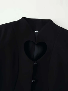 Detail of black blazer featuring heart-shaped cutout and small round bead buttons