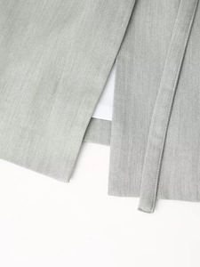 Detail of light gray cotton-linen fabric showing slit hem and matching narrow waist belt