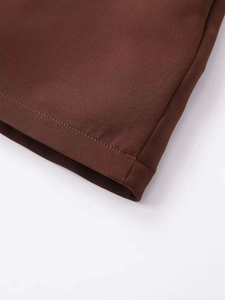 Detail shot showing the precise hem stitching and woven texture of the brown skirt fabric