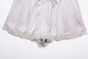 Detail shot of light purple satin shorts with delicate lace trim and silk texture