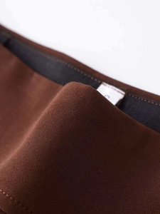 Macro shot of dark brown twill fabric texture with internal lining and white care label