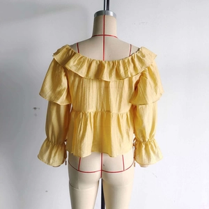 Detail view of yellow off-shoulder chiffon top with ruffled layers and flared sleeves