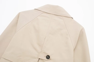 Detailansicht der beigen Jacke mit Raglanärmeln und dekorativem Knopfband am Rücken