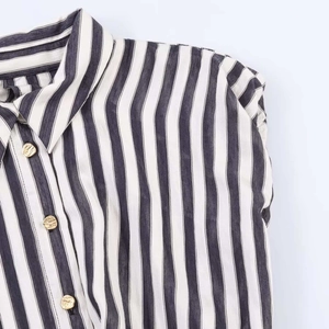 Detail shot of black and white vertical striped blouse with textured gold metal buttons