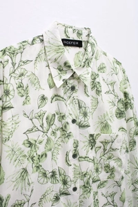 Détail de chemise à col avec imprimés botaniques verts et boutons contrastés