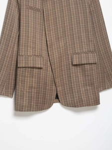 Détail d'un blazer à carreaux marron avec poches à rabat et texture à carreaux