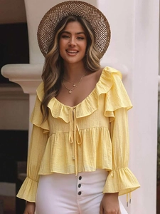 Detail of yellow pleated chiffon top with layered ruffles and neck tassel ties