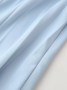 Gros plan sur la texture du tissu bleu clair avec d'élégants plis accordéon verticaux