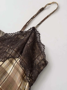 Détail du tissu à carreaux beige avec dentelle noire et fines bretelles réglables