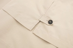 Detailansicht der khakifarbenen Twill-Struktur mit Nähten und Knopf an der kurzen Jacke