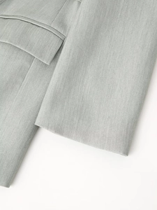 Detailed close-up of light gray blazer sleeve and flap pocket with fine twill texture