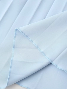 Détail du tissu plissé bleu clair montrant la texture et la couture de finition fine